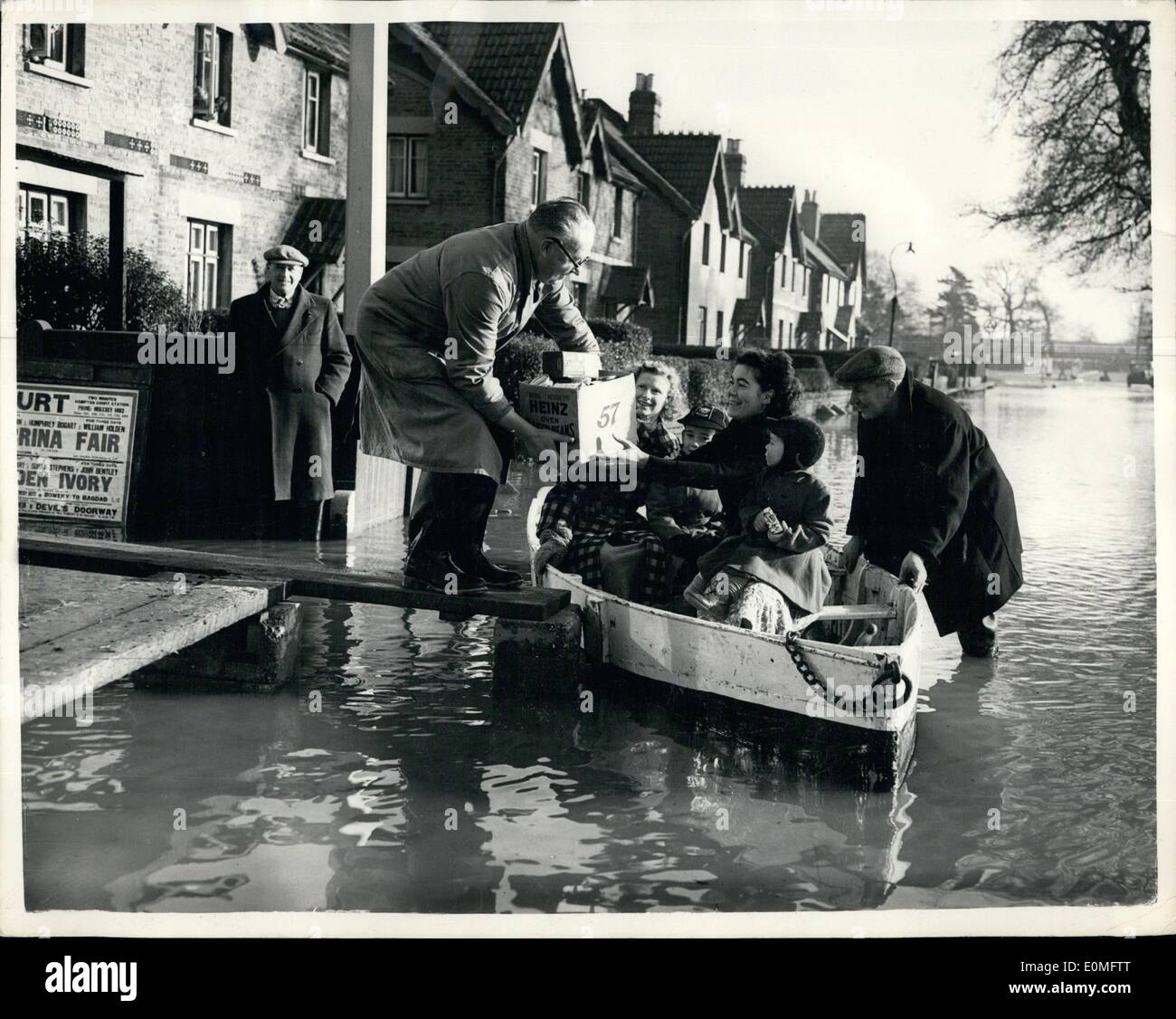 Jan. 01, 1955 - They Call This Highway - ''Summer Road''. Floods In East Molesey: Many residents of East Molesey, Surrey have to use boats when shopping these days - owing to the flood waters which this covered much of the surrounding areas- following the overflowing of the River Molesey. It is said that the flooding in the area is the worst for thirty years. Photo shows Mr. Tom Edwards a tradesman delivers a box full of groceries to Mrs. Barbara Marty who holds her three year old son Barry on her knee - as the latter goes shopping by boat - in flooded Summer Road, East Molesey. Stock Photo