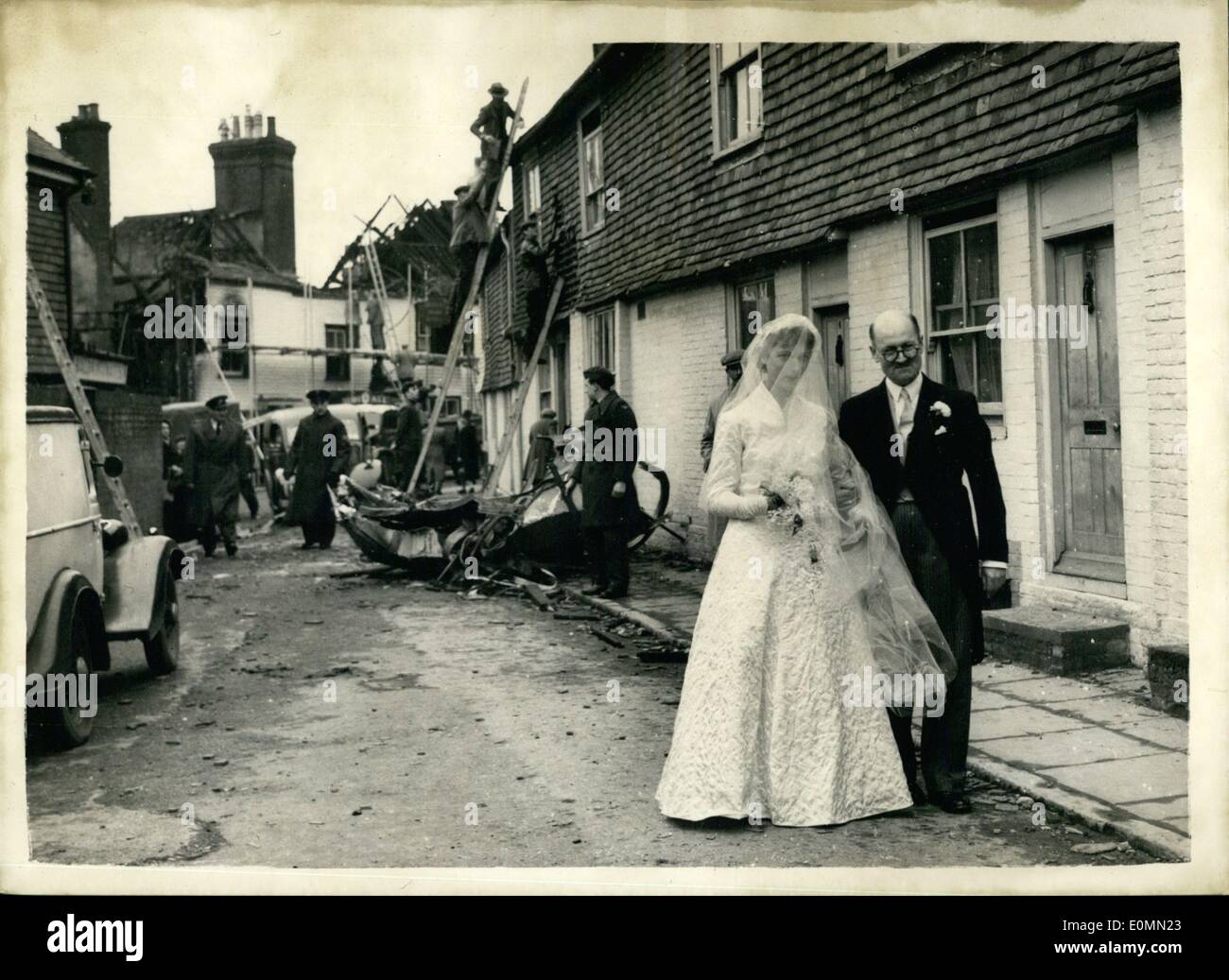 Jan. 01, 1956 - WEDDING AT THE VILLAGE CHURCH - SCENE OF THE AIR CRASH.. BRIDE ESCORTED THROUGH WRECKAGE BY HER UNCLE.. The wedding was held this afternoon at Wadhurst, Sussex, village church of 23 years old Miss Peggy Hazelden, of Hawkhurst and Mr. John Jackson of Wadhurst.. The guests had to pick their way through the rubble of wrecked buildings - for Wadhurst was the scene of yesterday's crash of an R.A.F. Meteor - in which two civilians and two servicemen lost their lives.. The only car allowed in the village was that of the bride and groom. Stock Photo