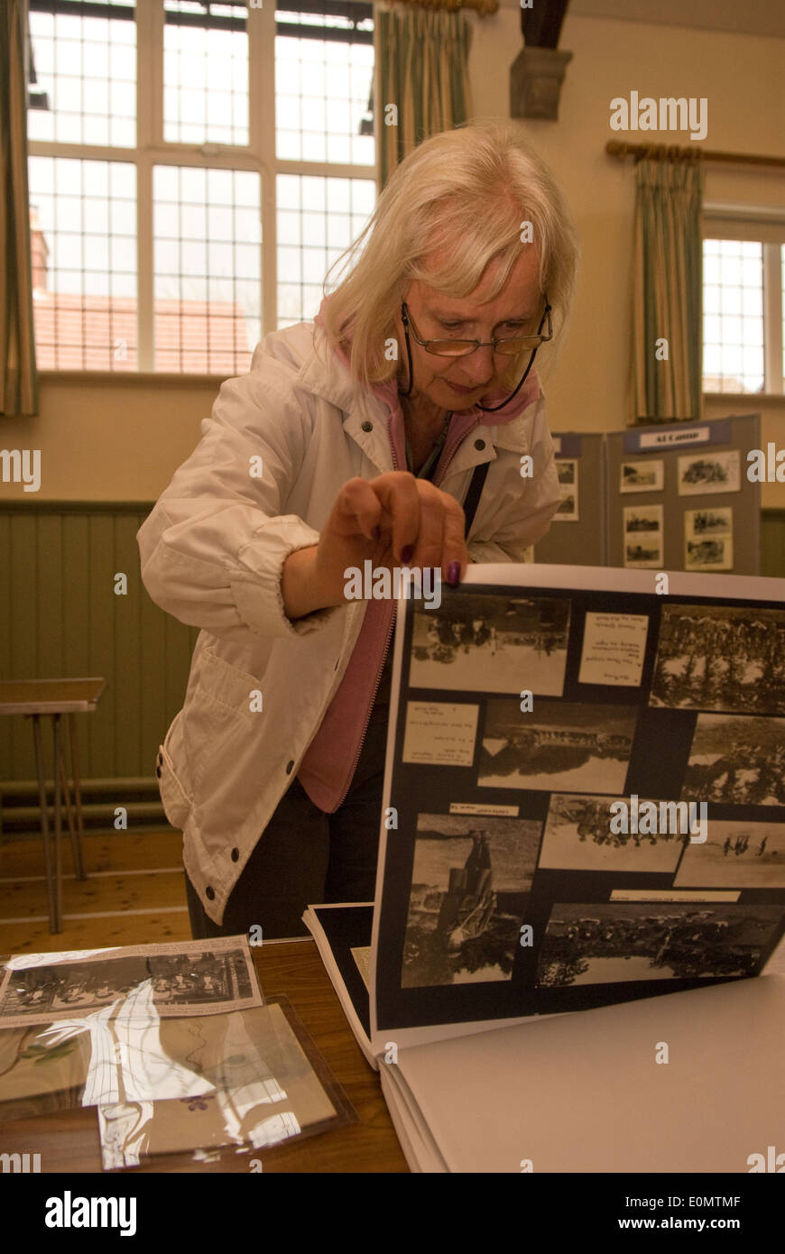 Elderly woman leafing through WW1 memorabilia at an exhibition documenting memories and artefacts from World War One... Stock Photo