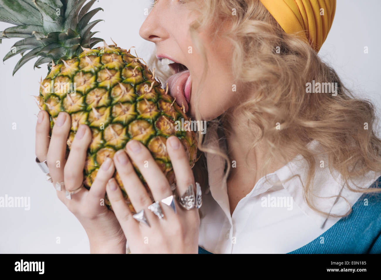 Concept of young woman loving pineapple so much she licks it like one would ice cream. Stock Photo