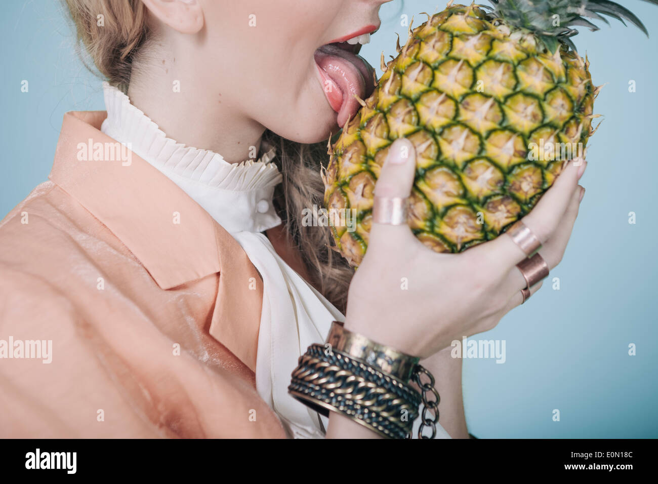 Concept of young woman loving pineapple so much she licks it like one would ice cream. Stock Photo