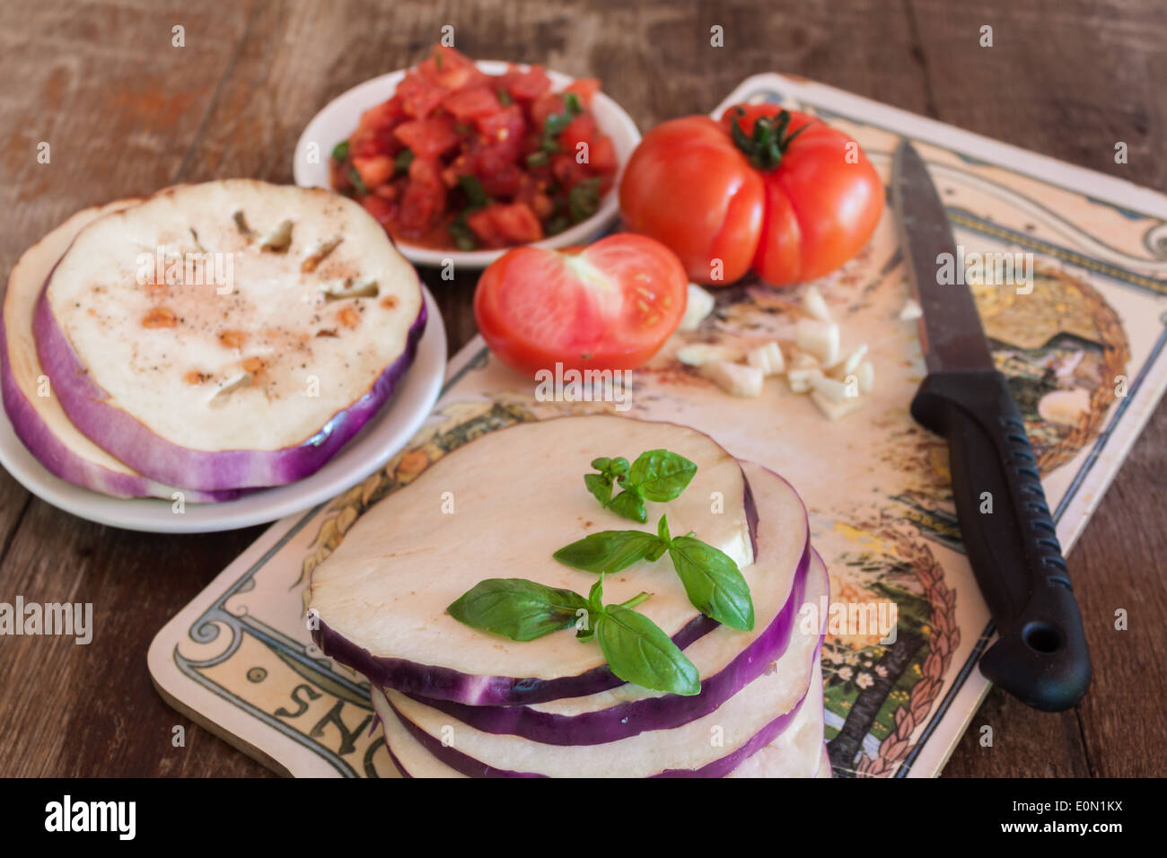 cook recipe eggplant sliced tomato chopped 'cutting board' closeup knife prepare table Stock Photo