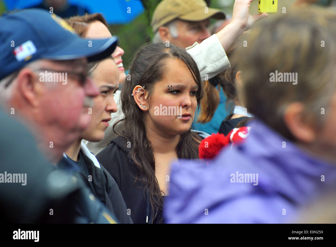 A woman with many piercings stand amidst a crowd. Stock Photo