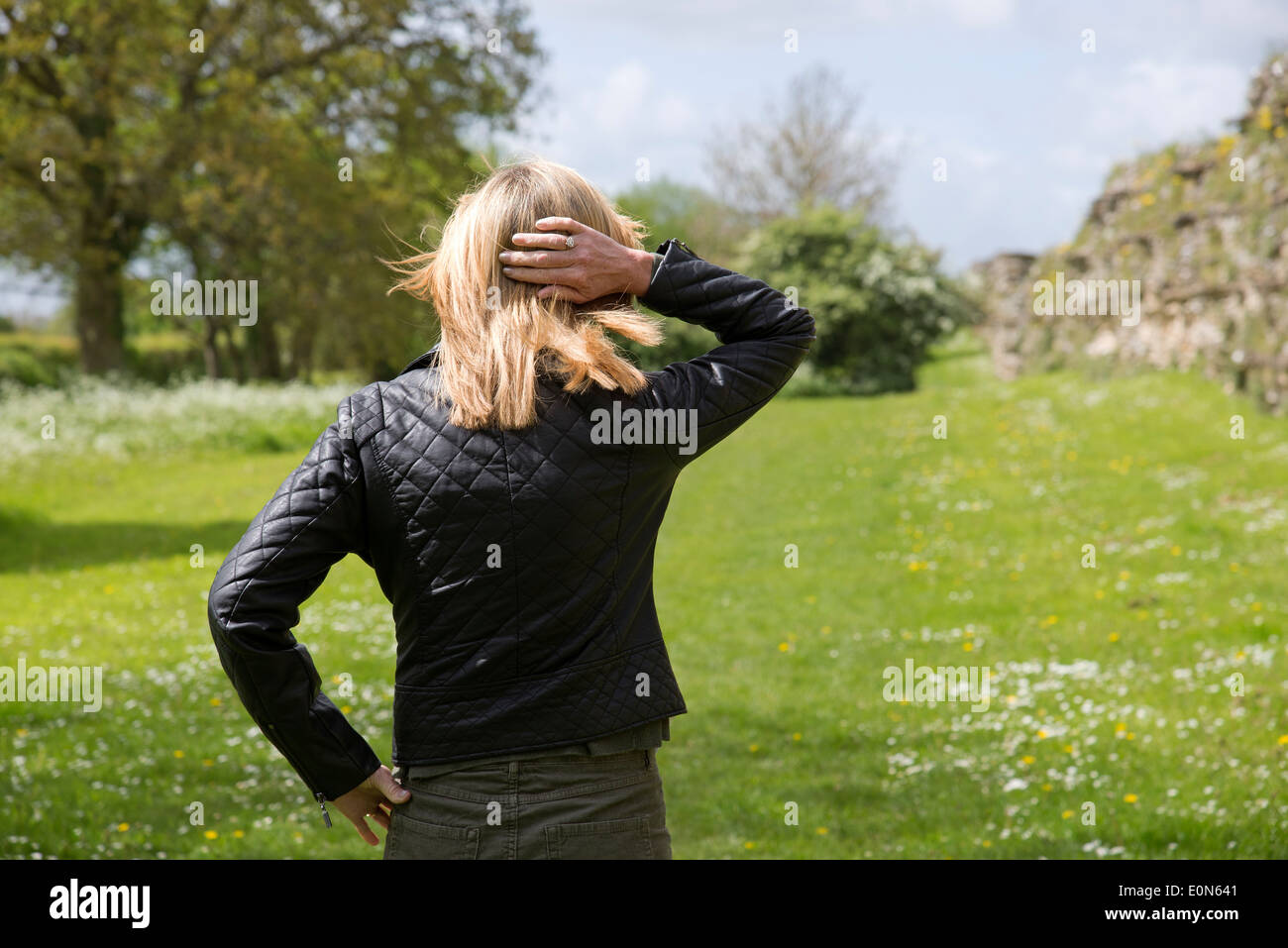 Woman standing alone in a field with back to the camera Stock Photo
