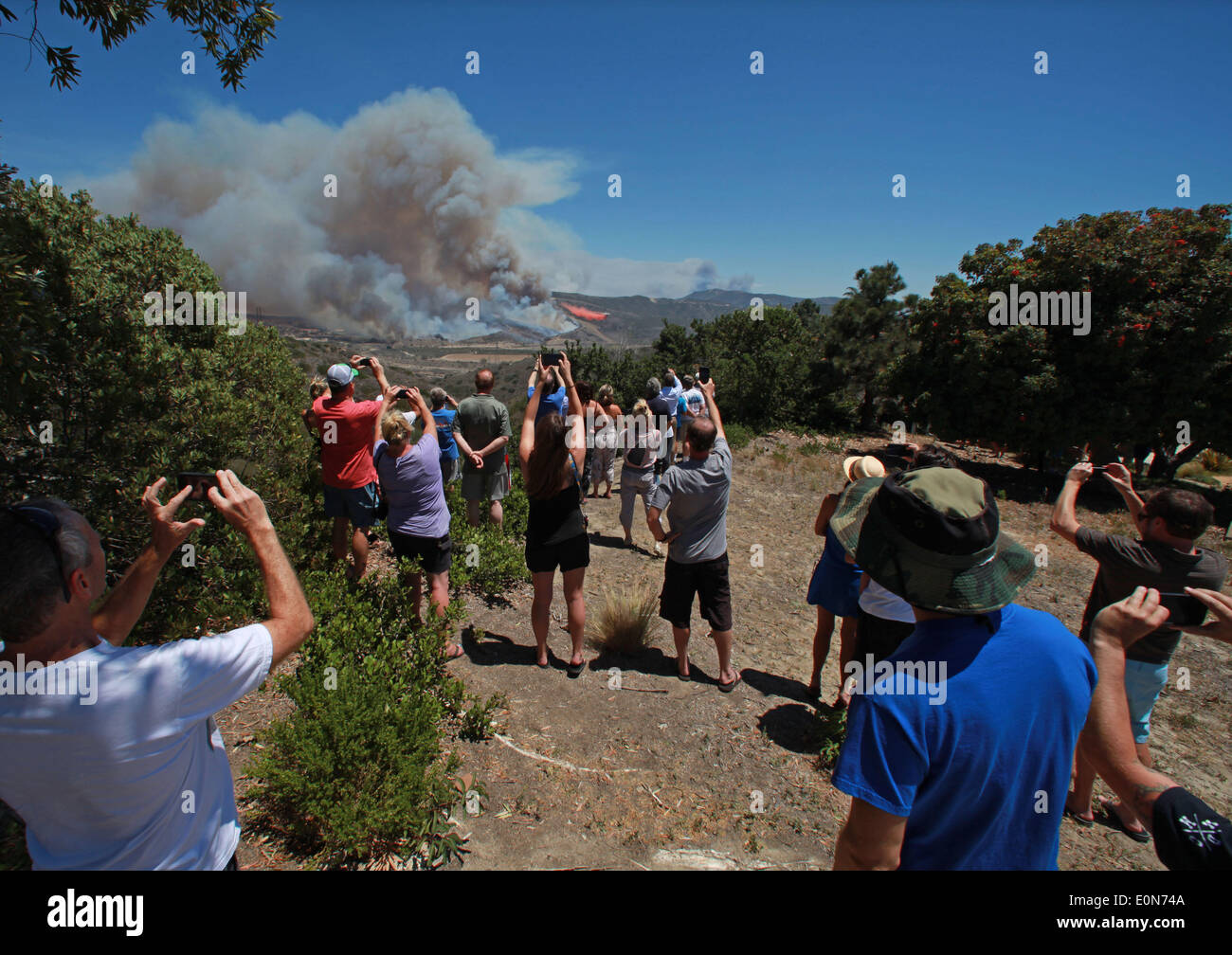 San Clemente, California, USA. 16th May, 2014. San Clemente residents watch and take pictures with cellphones of fire fighting aircraft as the Las Pulgas wildfire burns inside Camp Pendleton marine Base. The wildfire in the western region of Camp Pendleton has grown to 8,000 acres burned, base officials confirmed, known as the Las Pulgas Fire, is 5 percent contained, officials said. California firefighters have continued to battle wildfires, which have scorched more than 11,000 acres and caused thousands to evacuate. Credit:  ZUMA Press, Inc./Alamy Live News Stock Photo