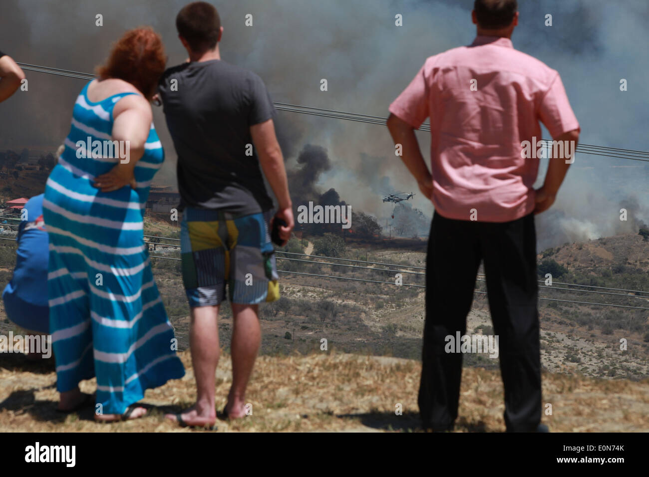 San Clemente, California, USA. 16th May, 2014. San Clemente residents watch fire fighting helicopters douse water on the Las Pulgas wildfire burns Camp Pendleton marine Base. The wildfire in the western region of Camp Pendleton has grown to 8,000 acres burned, base officials confirmed, known as the Las Pulgas Fire, is 5 percent contained, officials said. California firefighters have continued to battle wildfires, which have scorched more than 11,000 acres and caused thousands to evacuate. Credit:  ZUMA Press, Inc./Alamy Live News Stock Photo