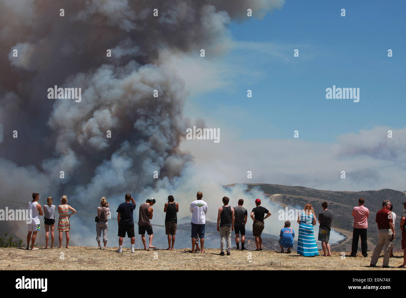 San Clemente, California, USA. 16th May, 2014. San Clemente residents watch and take pictures with cellphones of fire fighting aircraft as the Las Pulgas wildfire burns inside Camp Pendleton marine Base. The wildfire in the western region of Camp Pendleton has grown to 8,000 acres burned, base officials confirmed, known as the Las Pulgas Fire, is 5 percent contained, officials said. California firefighters have continued to battle wildfires, which have scorched more than 11,000 acres and caused thousands to evacuate. Credit:  ZUMA Press, Inc./Alamy Live News Stock Photo
