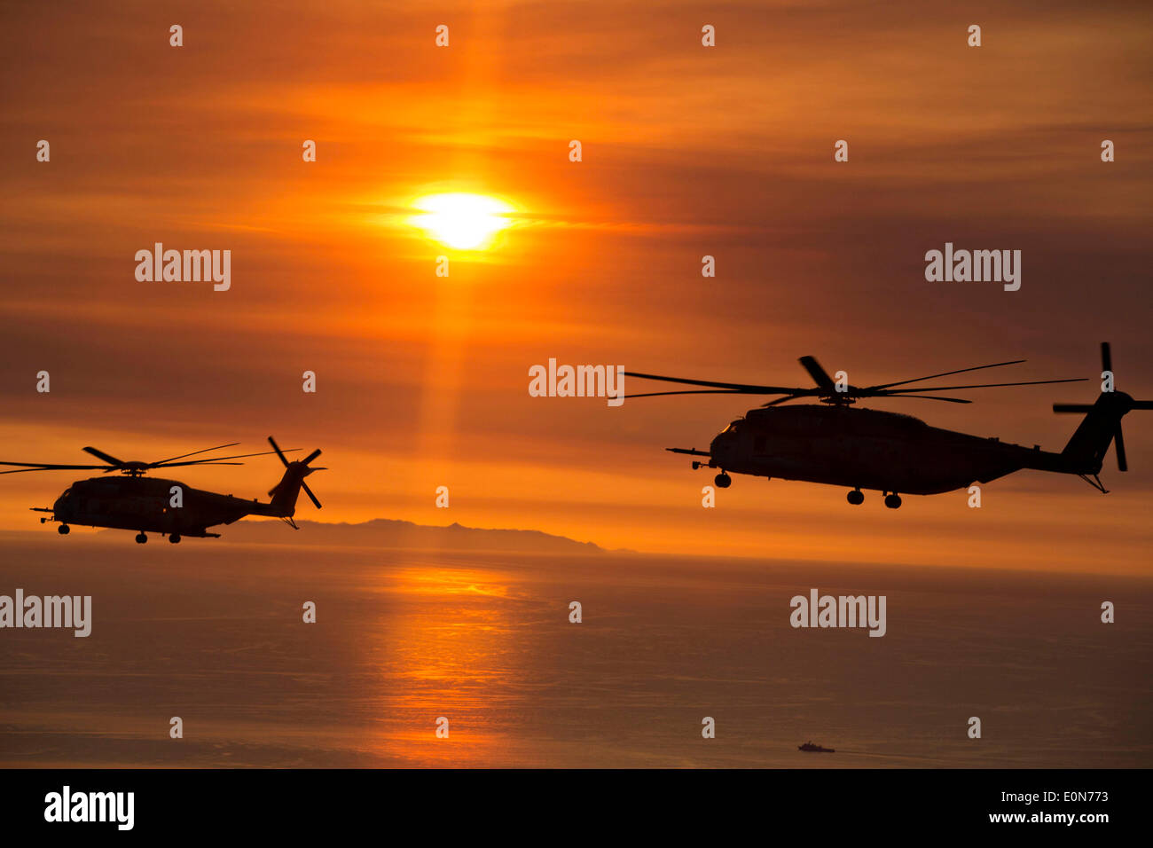 US Marine Corps CH-53D Sea Stallion helicopters are silhouetted against a sunset enhanced by smoke from the Cocos wildfire as they assist in firefighting May 15, 2014 around San Marcos, California. Evacuations forced more than 13,000 people from their homes as the fire burned across San Diego County. Stock Photo