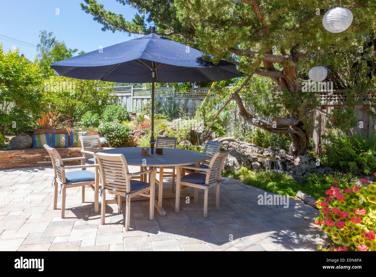 Beautiful backyard landscaping with stream water feature behind patio dining table Stock Photo