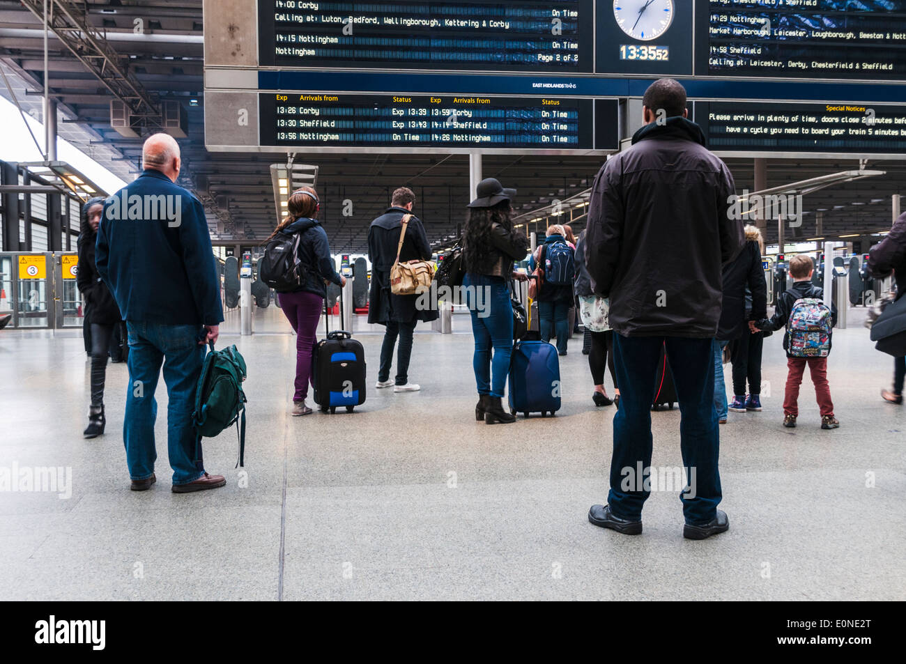Train passengers standing on the concourse looking at the departures board at St Pancras train station in London Stock Photo