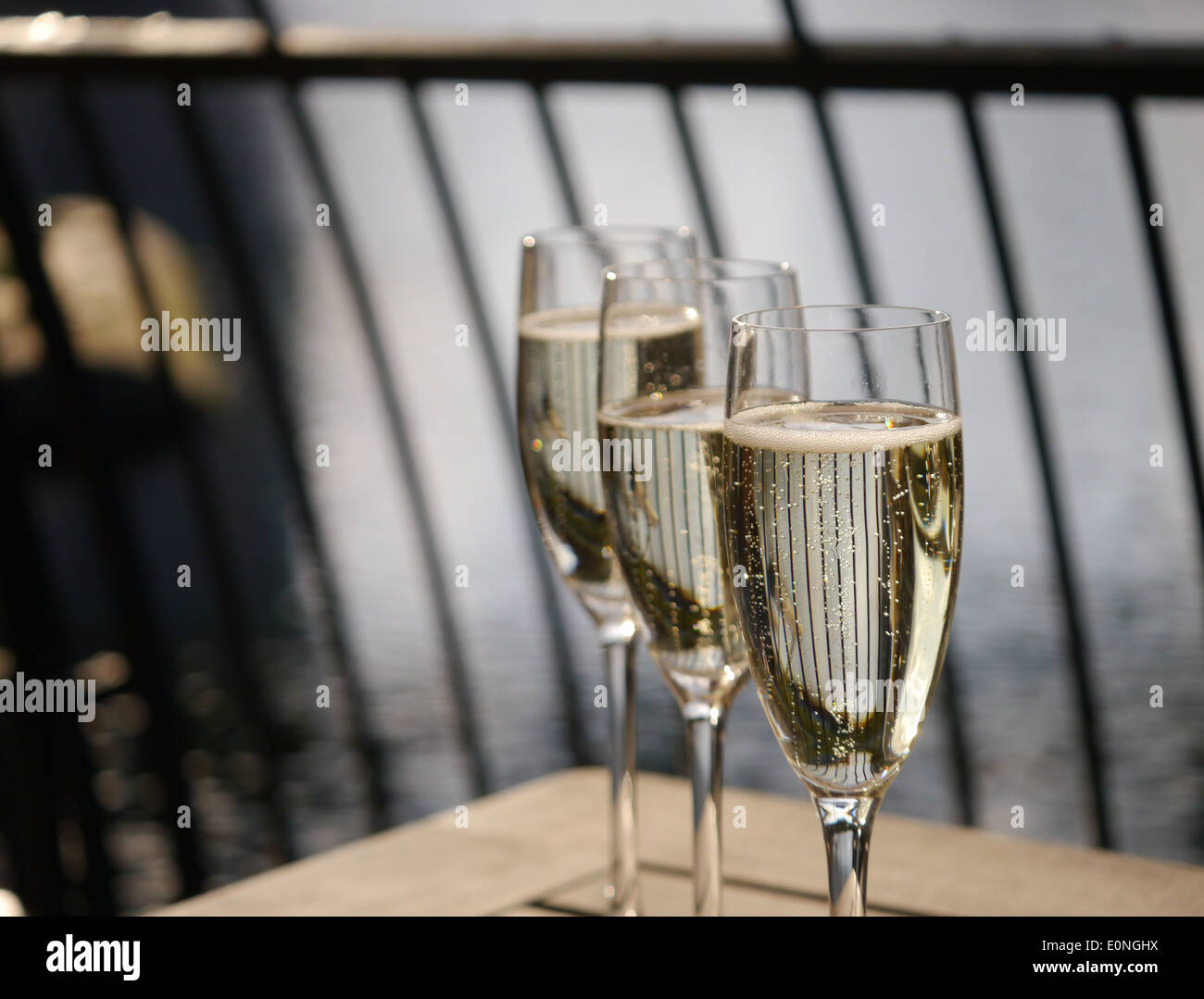 Three champagne glasses in a row on a wooden table Stock Photo