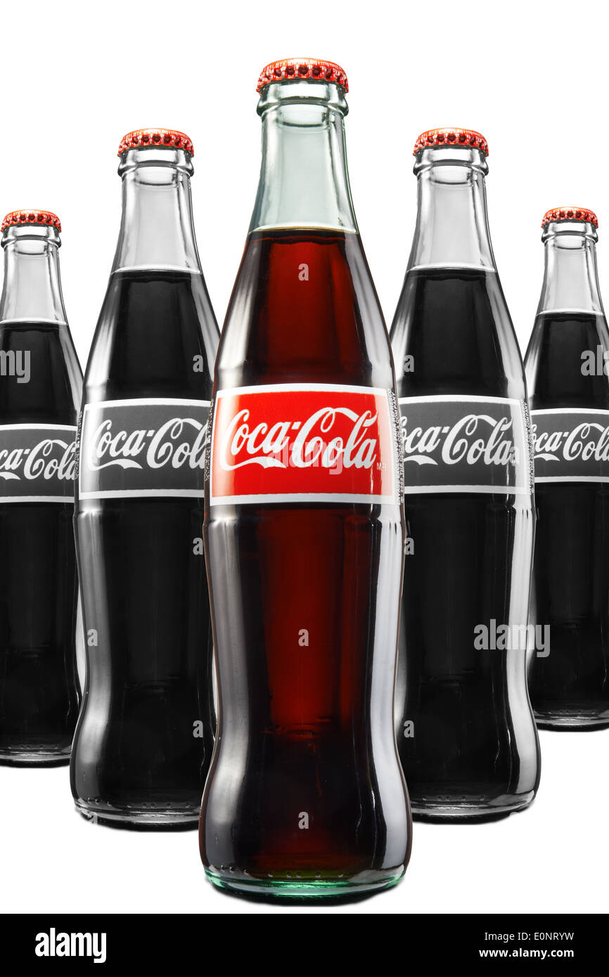 Coke Bottles lined up in a triangular formation with the first one in color as a Product Shot Stock Photo