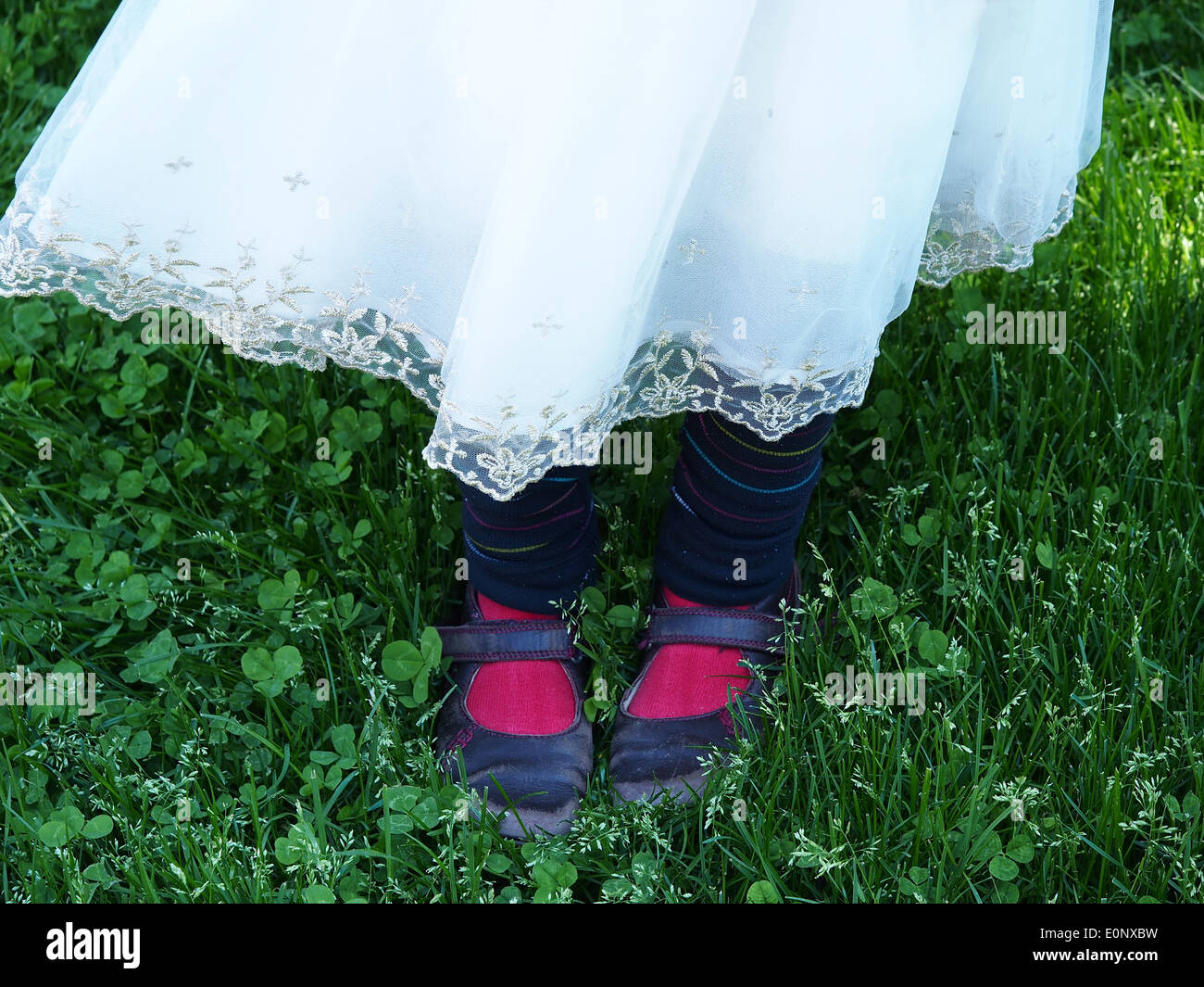 young girl in white lace dress red socks and shoes Stock Photo