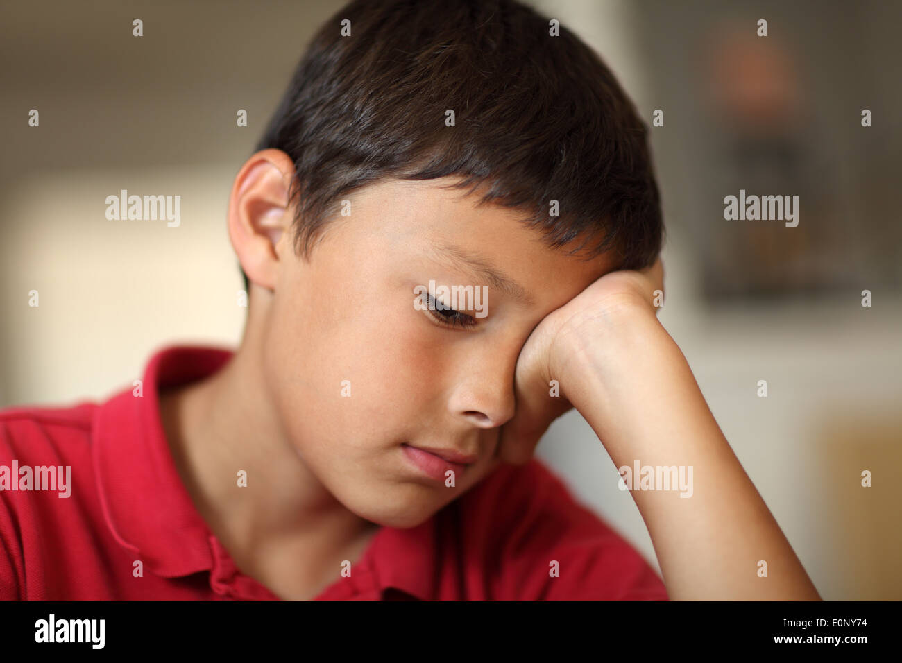 Young very bored student boy with hand covering his eye - very shallow depth of field with copy space Stock Photo
