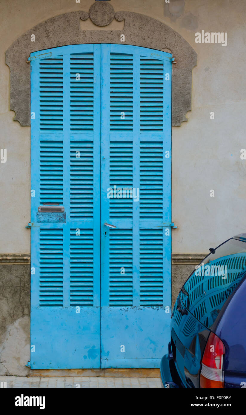 Typical Mallorquin architecture detail - turquoise door reflecting in window of blue car. Mallorca, Balearic islands, Spain. Stock Photo