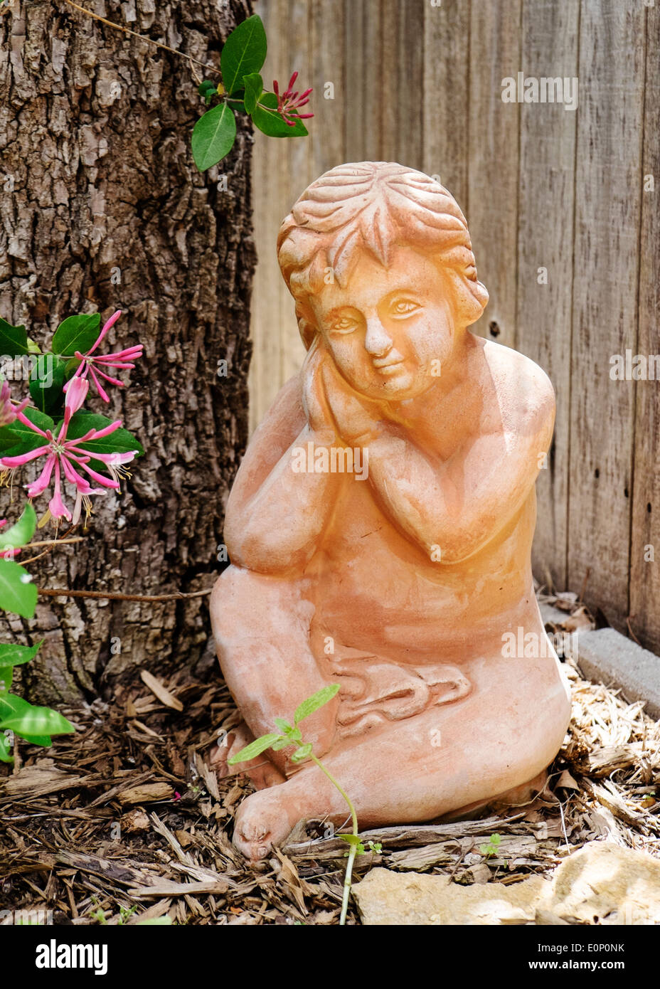 Garden statuary of a cherub next to a tree in a home's back yard. Stock Photo