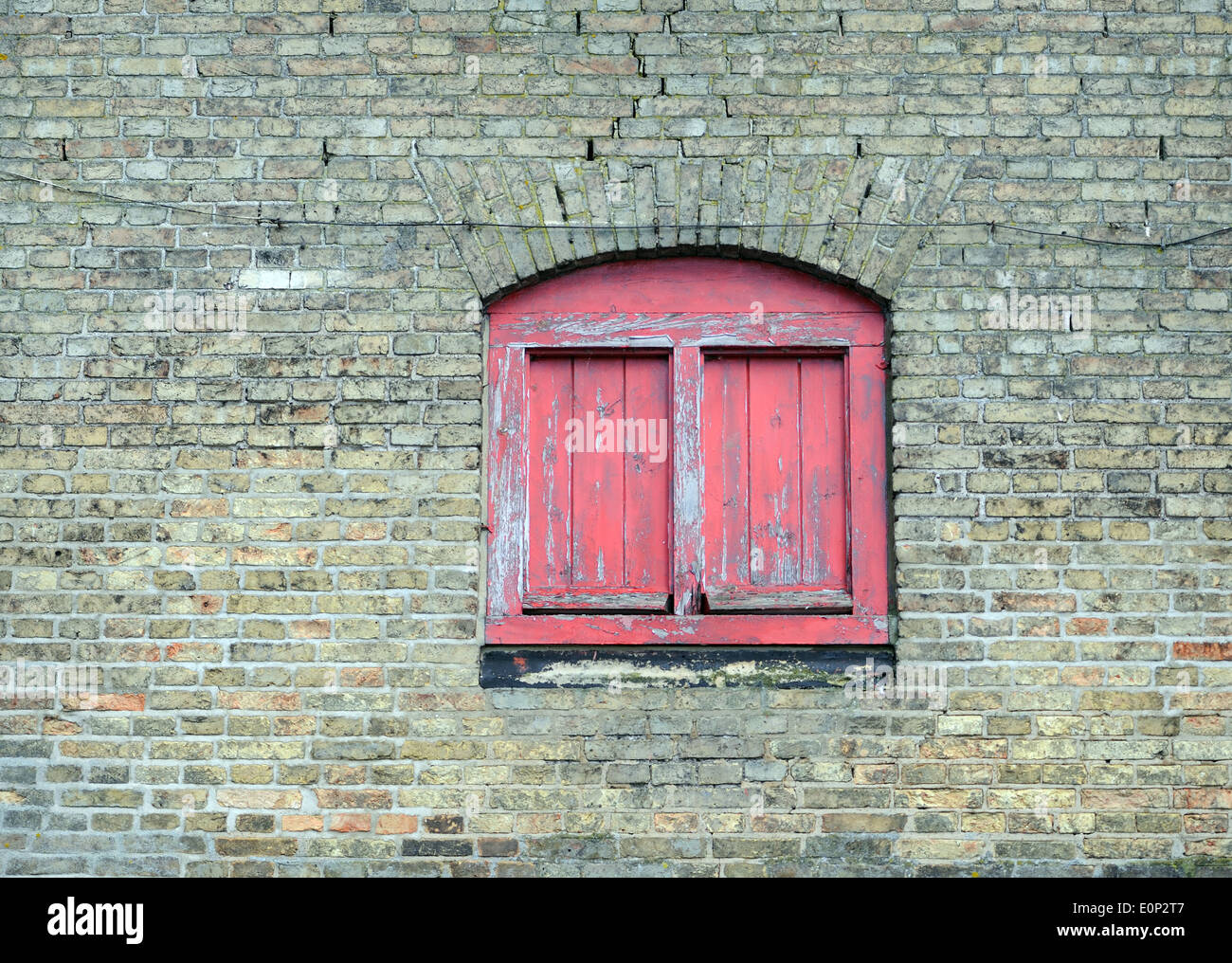 Faded red painted window in a warehouse wall. King's Lynn, Norfolk. UK. Stock Photo