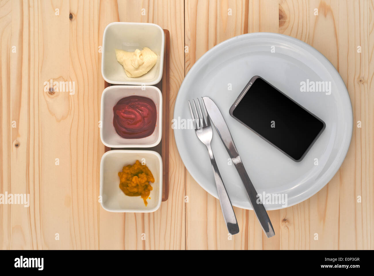 Mobile smart phone served as dinner on white plate. Concept of information absorption process. Stock Photo