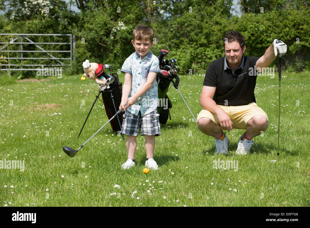 Five year old boy taking golf lesson with his father Hampshire England