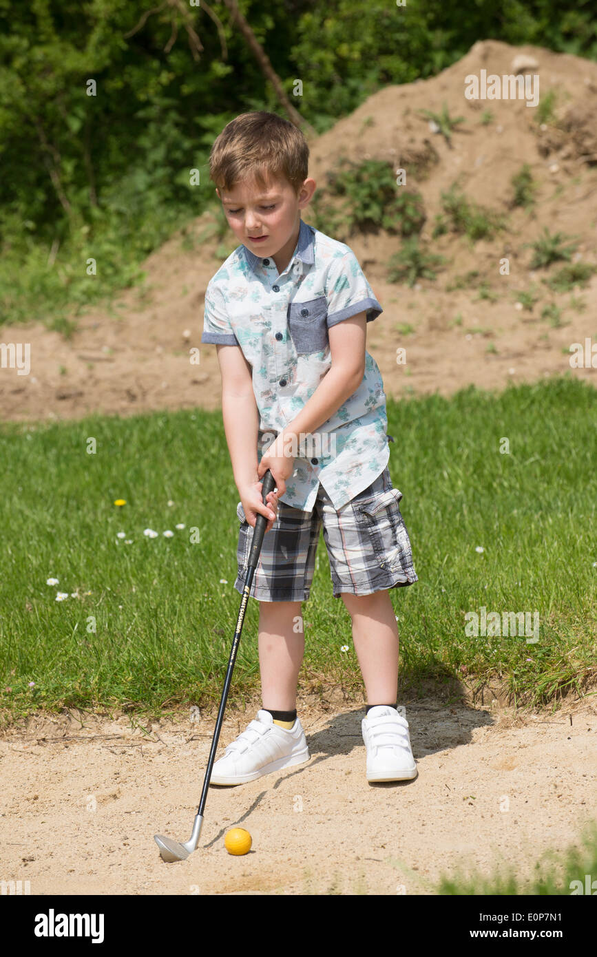 Little boy aged 5 years and a keen golfer playing out of a bunker using a  specially cut down sized golf club. Hampshire England Stock Photo - Alamy