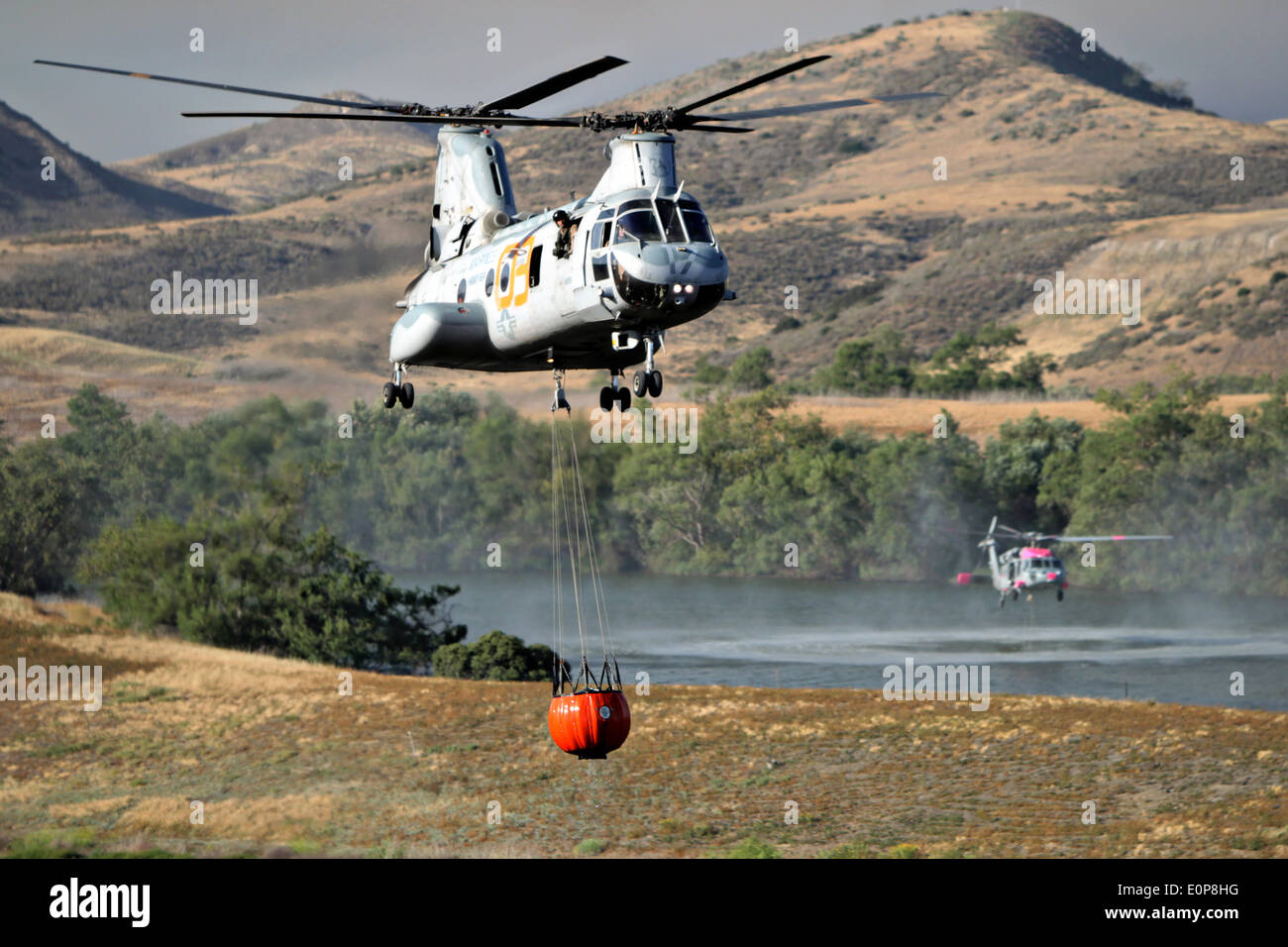 US Marine Corps CH-46 Sea Knight helicopters fills a bambi buckets to fight the Tomahawk wildfire as it continues to burn May 16, 2014 around Camp Pendleton, California.  Evacuations forced more than 13,000 people from their homes as the fire burned across San Diego County. Stock Photo