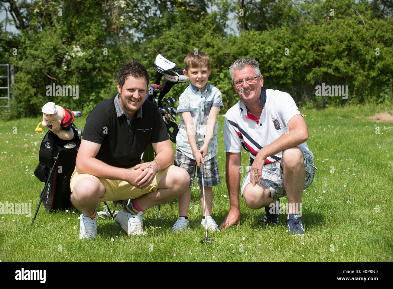 Golfers from three generations Grandfather Father son grandchild. A golfing family Stock Photo