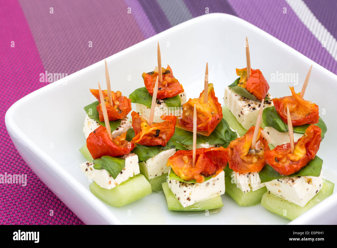 Plate of small feta, cucumber and tomato appetizers on toothpicks Stock