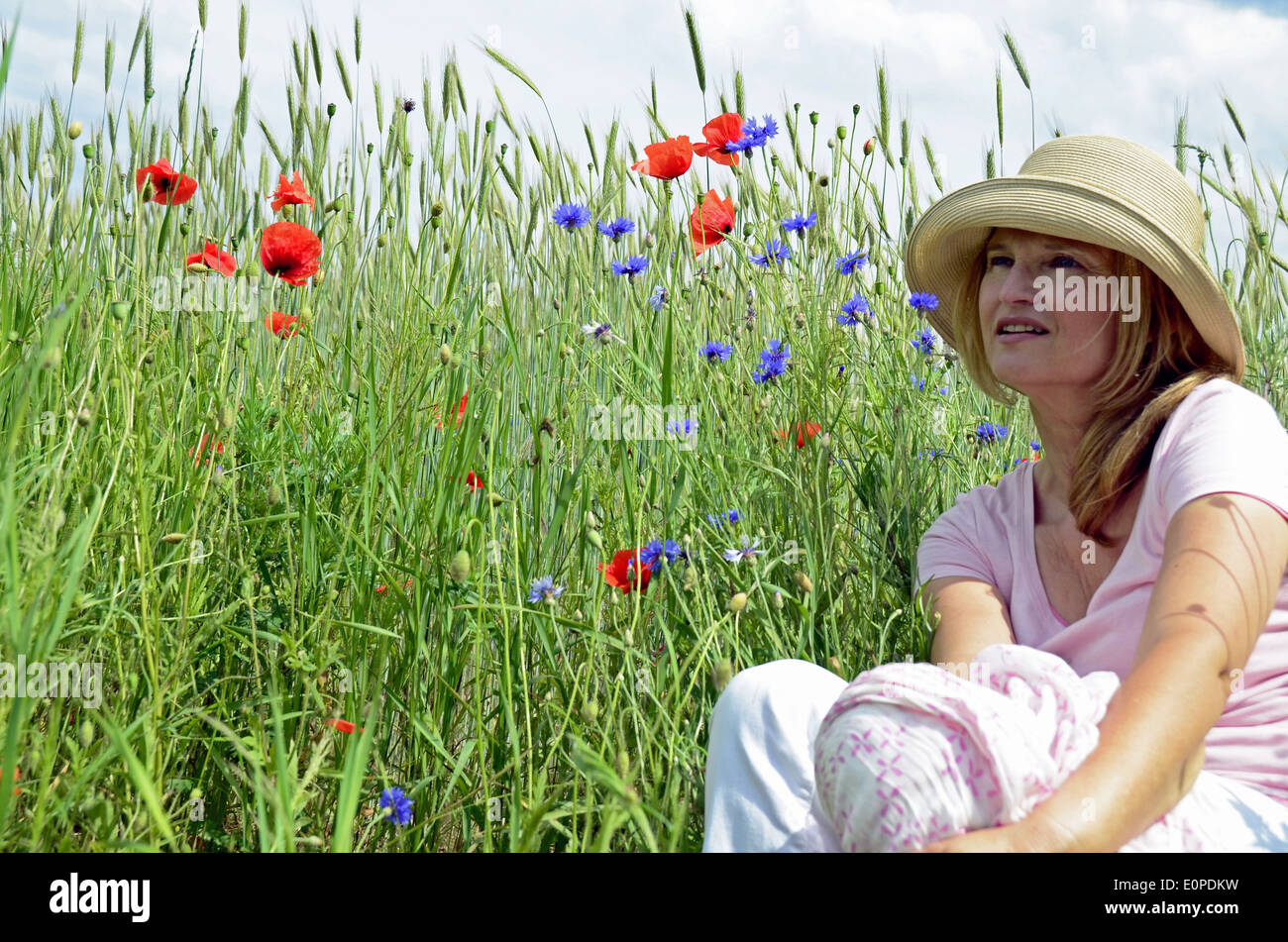 Woman with hat sitting on meadow Stock Photo
