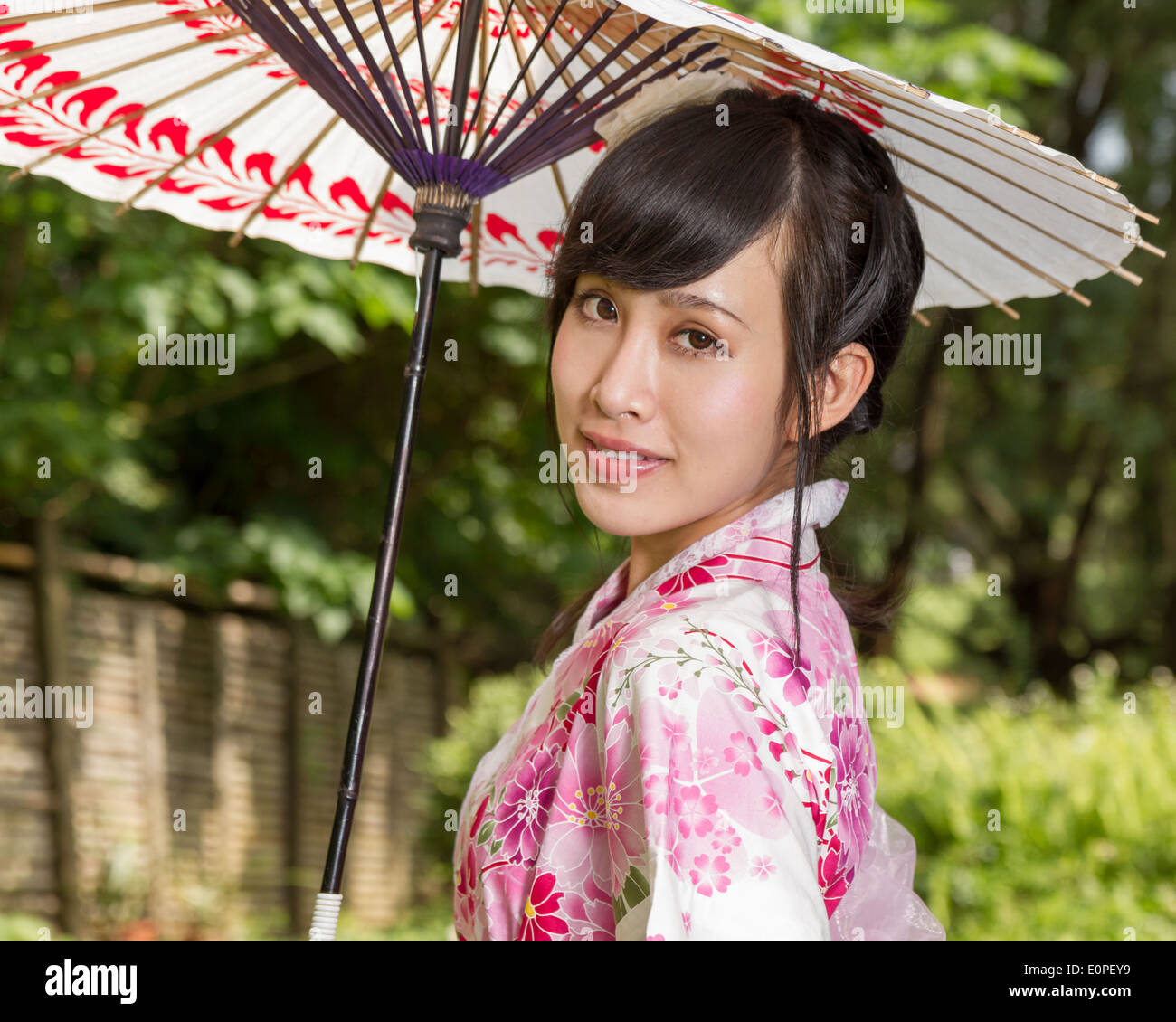 Asian woman in a kimono in a Japanese style garden holding an umbrella Stock Photo Alamy