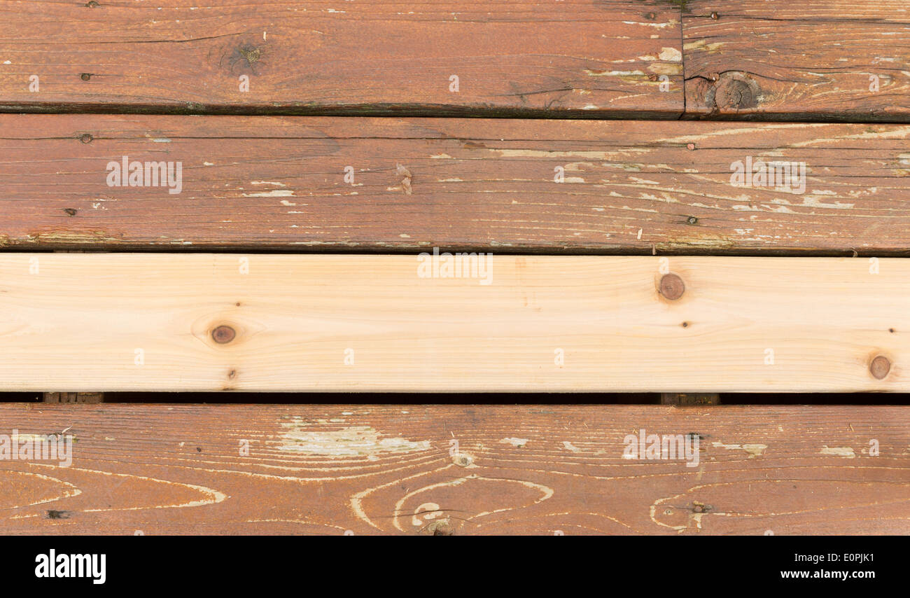 Horizontal photo of a single new cedar wooden board next to fading wood on outdoor deck Stock Photo