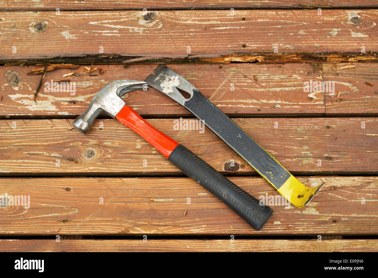 Horizontal photo of old hammer and pry bar next to rotting wood on cedar wooden deck Stock Photo