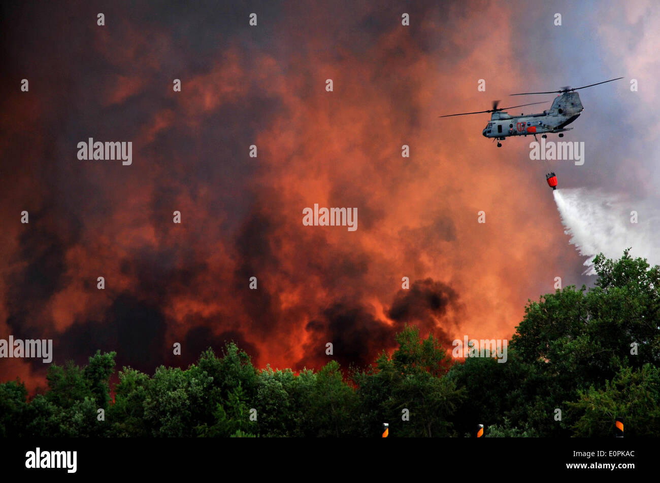 A US Marine Corps helicopter carries water using a Bambi bucket to help fight the Tomahawk and Las Pulgas wildfires as they burn the foothills May 17, 2014 around Camp Pendleton, California.  Evacuations forced more than 13,000 people from their homes as the fire burned across San Diego County. Stock Photo