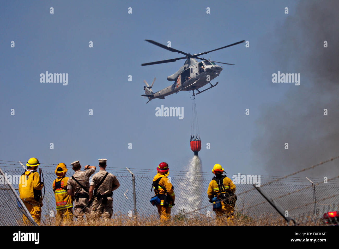 A US Marine Corps helicopter drops water from a Bambi bucket to help fight the Tomahawk and Las Pulgas wildfires as they burn the foothills May 17, 2014 around Camp Pendleton, California.  Evacuations forced more than 13,000 people from their homes as the fire burned across San Diego County. Stock Photo