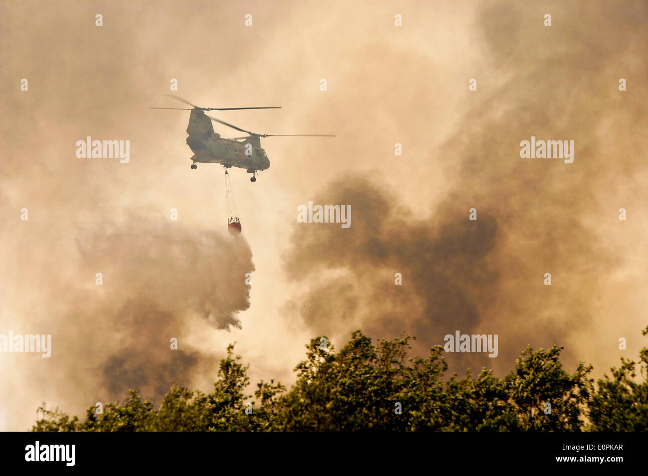 A US Marine Corps helicopter carries water into a Bambi bucket to help fight the Tomahawk and Las Pulgas wildfires as they burn the foothills May 16, 2014 around Camp Pendleton, California.  Evacuations forced more than 13,000 people from their homes as the fire burned across San Diego County. Stock Photo