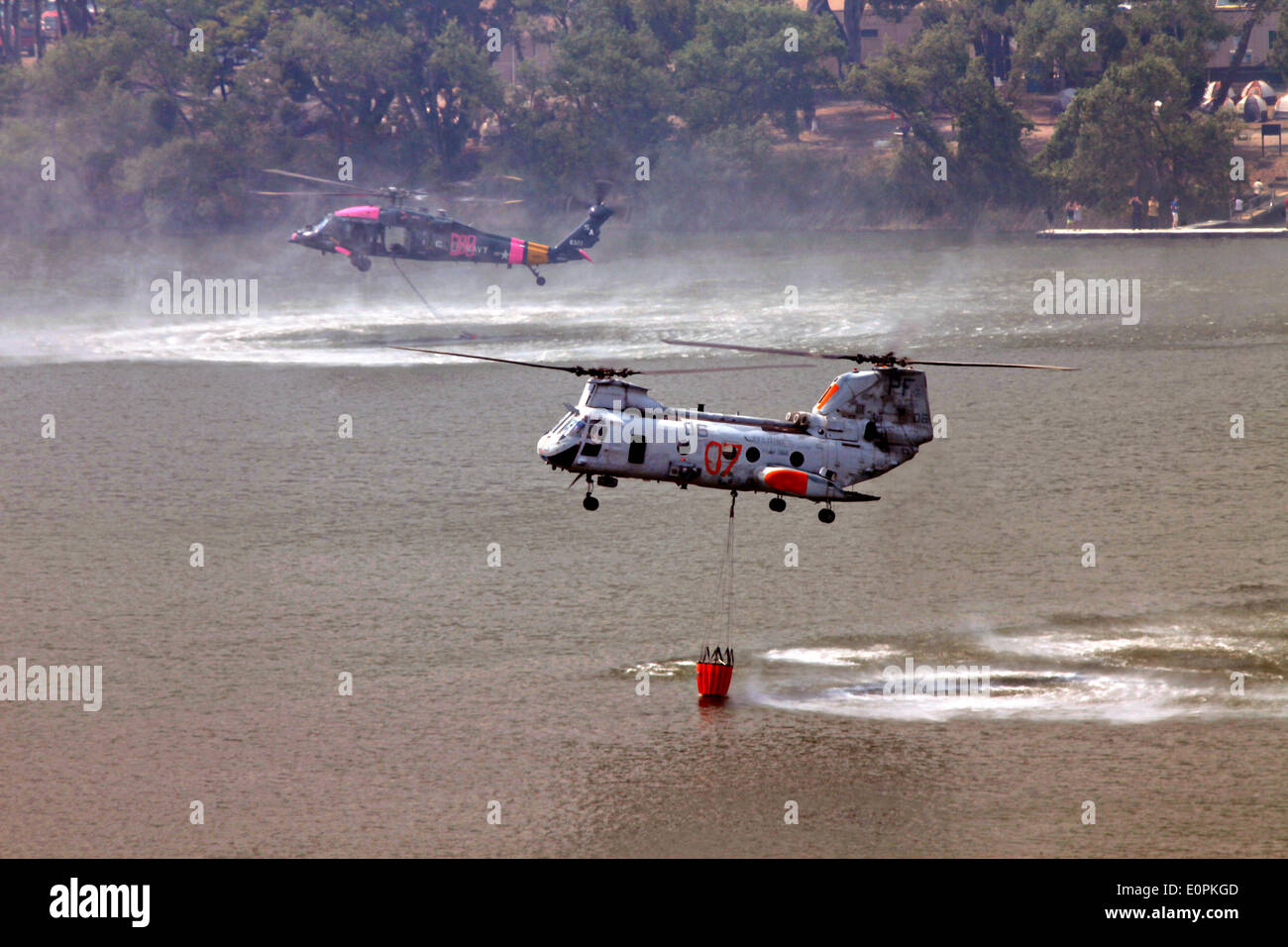 US Marine Corps helicopters load water using a Bambi bucket to help fight the Tomahawk and Las Pulgas wildfires as they burn the foothills May 16, 2014 around Camp Pendleton, California.  Evacuations forced more than 13,000 people from their homes as the fire burned across San Diego County. Stock Photo