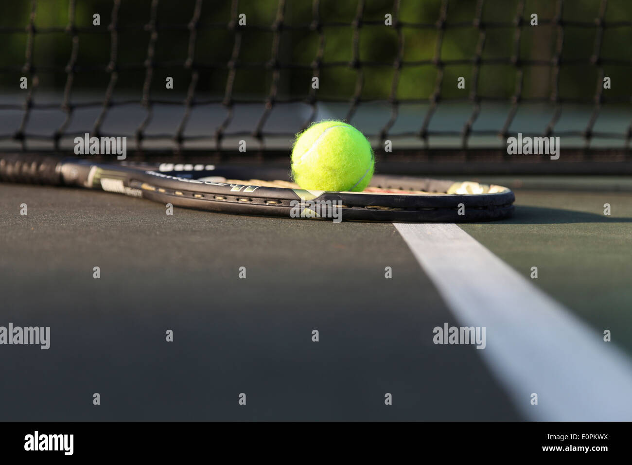 Tennis racket and ball on court by net. Stock Photo
