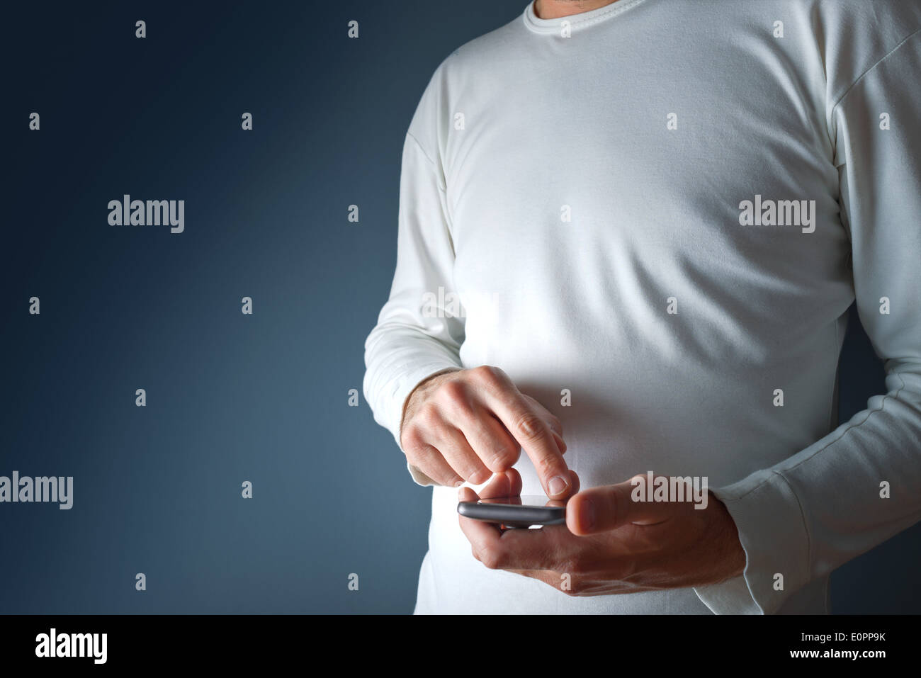 Man in white shirt using mobile smart phone device. Stock Photo