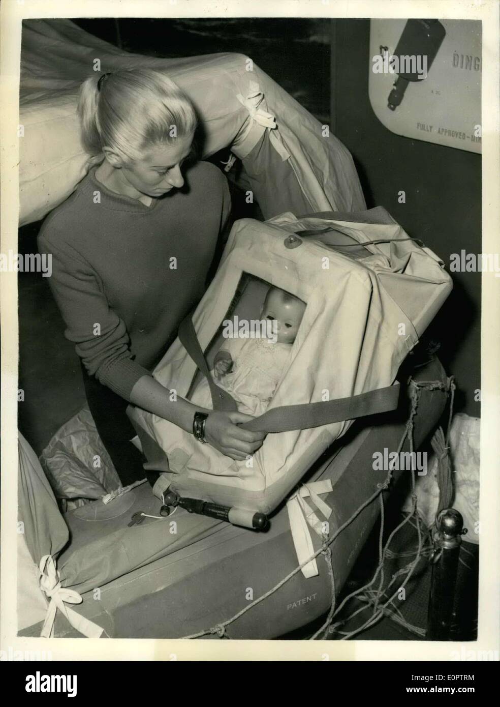 Dec. 31, 1956 - Preparing Fort The National Boat Show: Photo Shows Marie Dunsmore, of New Zealand, demonstrates the Baby's Floating Survival Cot - at Olympia today, where the National Boat on tomorrow. The Cots a life saving device for airlines. Ships and boats, is a completely closed in cot which, with its self-erecting hoof and canopy, not only provides flotation, but also protection from waves, spray, rain, wind and exposure. The baby, wrapped in the usual blanket, may be tied down inside the cot with two bands of fabric before an aircraft ditches Stock Photo