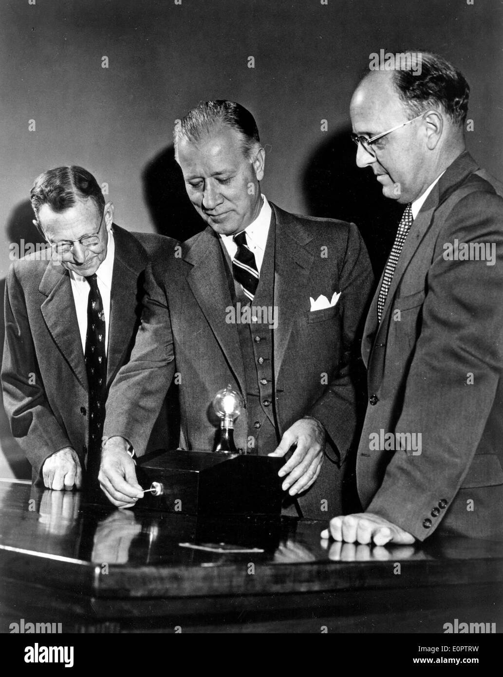 Jan 01, 1957 - Schenectedy, New York, USA - (File Photo, c1957) From left, Dr. WILLIAM COOLIDGE, director-emeritus of research at GE; RALPH J. CORDINER, GE President GE; and Dr. GUY SUITS, GE VP and director of research; light a incandescent bulb designed to last 100-years that will burn continuously on Thomas Edison's desk in General Electric's headquarters. Stock Photo