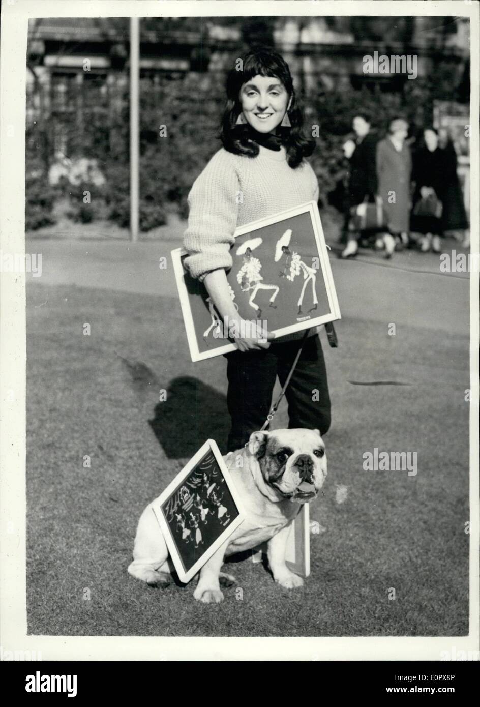 Apr. 04, 1957 - Open Air Art Show in Embankment Gardens. The tenth annual display of paintings at the Victoria Embankment Garden opened today. It is organised by the L.C.C. Keystone Photo Shows: Mrs. Rosemary Harrison of Hampstead, gets a helping hands from her bulldog ''Block Buster Timbo'' - as eh arrives with her paintings. Stock Photo