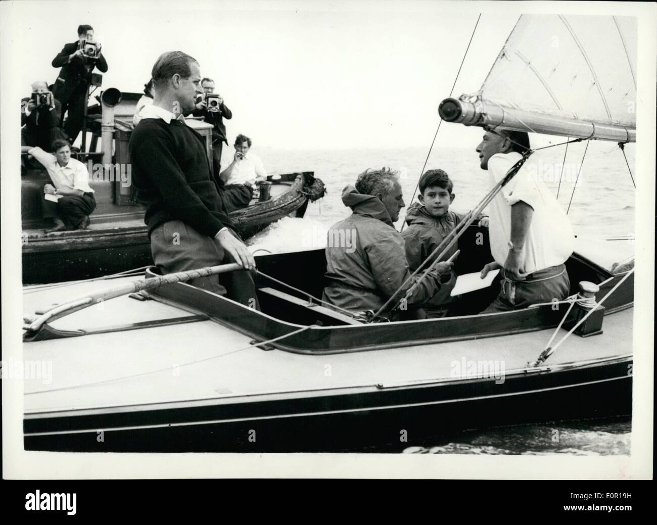 Aug. 08, 1957 - Prince Charles goes yacht racing with his father. Duke at the Tiller Aboard:Prince Charles accompanied by his father the Duke of Edinburgh in the ''Bluebottle'' - when competing in a Dragon class race - during the   today. Photo shows the Duke at the  with Prince Charles and  fox seated - and on right Lieut. Commander A.T. Easton - in the ''Bluebottle'' at Cowes today. Stock Photo