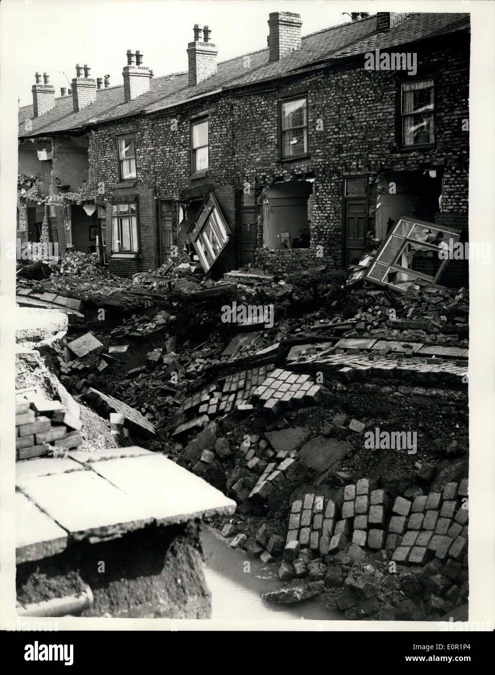 Sep. 13, 1957 - Thirteen Houses - Two Shops Swallowed By 120ft. Crater In Lancashire street: A ''creeping earthquake'' is swallowing houses - one after another - in the Lancashire town of Farnworth. By last night thirteen houses and two shops have a been wrecked - and more than 350 people have been evacuated - but nobody was hut.. The crater was started by a fracture in a sewage drain 10ft. down. It is of the land collapse would increase - the whole area lives in fear of their homes disappearing Stock Photo