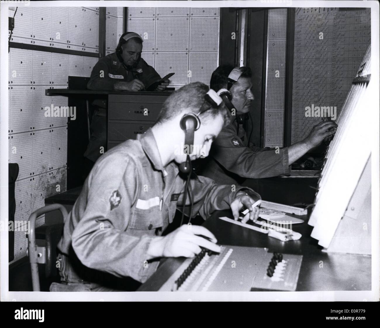 May 05, 1958 - Fort Monmouth, N.J.:- Highly trained men operating the new flight control van built at the US Army Signal Research and Development Laboratory, Fort Monmouth, New Jersey, keep their fingers on the pulse of the Army;s tactical aircraft. The mobile control van, with a 10-foot communication and flight-charting console, keeps the fixed-wing aircraft and helicopters. SP3 Charles Bowen (foreground) (Seattle, Wash.,) the assistant flight controller, receives a flight plane, while SP3 Robert W. Parton (Oklahoma City, Okla Stock Photo