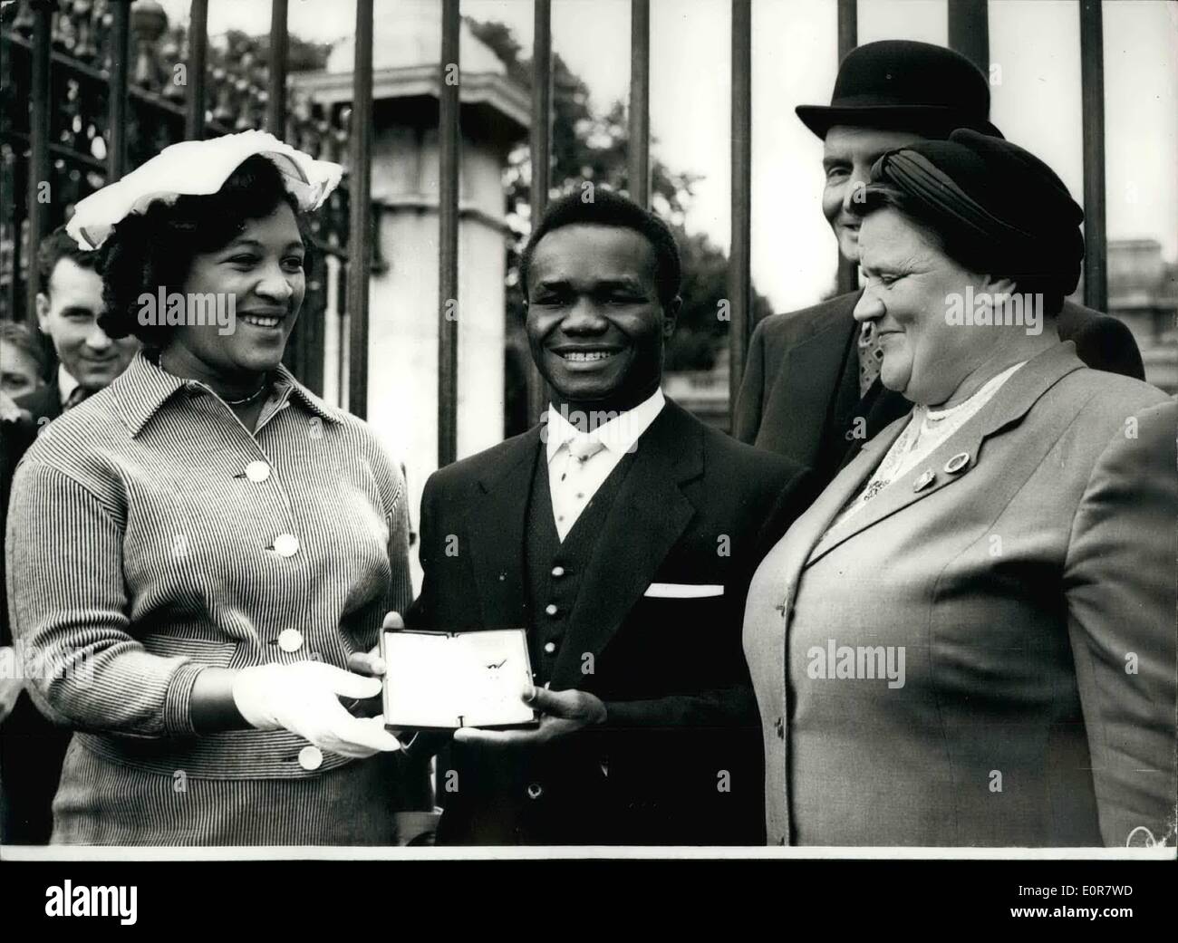 Jul. 07, 1958 - Investiture at Buckingham Palace. Hogan ''Kid'' Bassey Receives the M.B.E. Photo Shows Hogan ''Kid'' Bassey - the world featherweight champion - shows his M.B.E. to his wife and Mrs. Bessie Braddock M.P. - after having received it at the Buckingham Palace Investiture this morning. Stock Photo