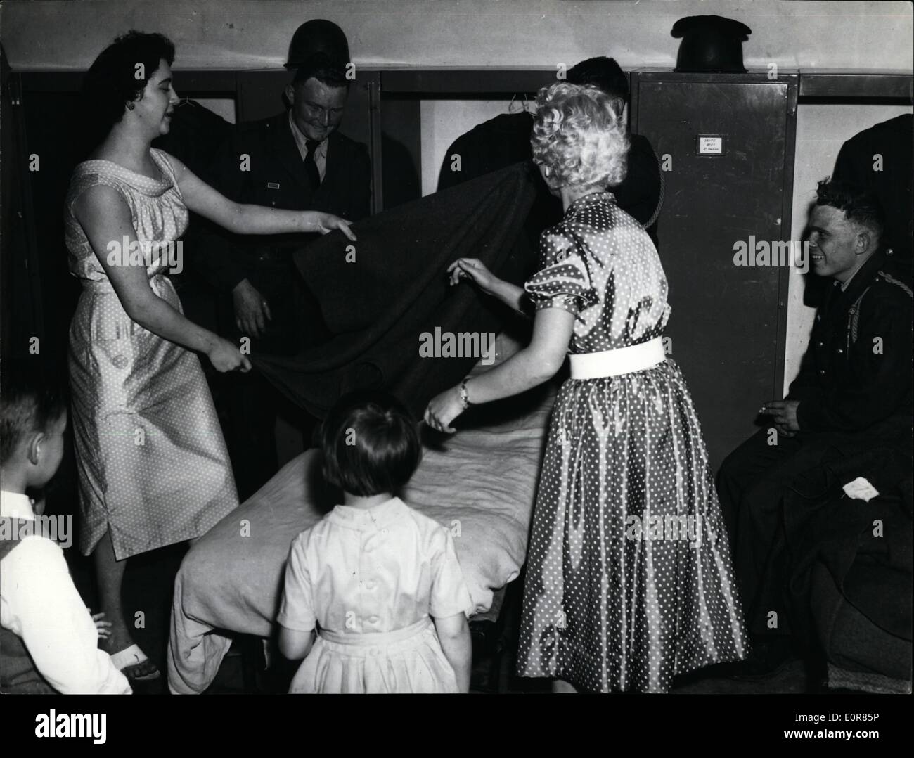 Jul. 07, 1958 - BARRACKS OPEN TO PUBLIC FOLLOWING THE DECISION OF THE FRENCH WAR OFFICE THE PUBLIC CAN NOW VISIT MILITARY BARRACKS ON CERTAIN DAYS. OPS.: WATCHED BY LAUGHING RECRUITS, SOME FAIR VISITORS ARE TRYING TO LEARN HOW TO MAKE A PROPER SOLDIER'S BED Stock Photo