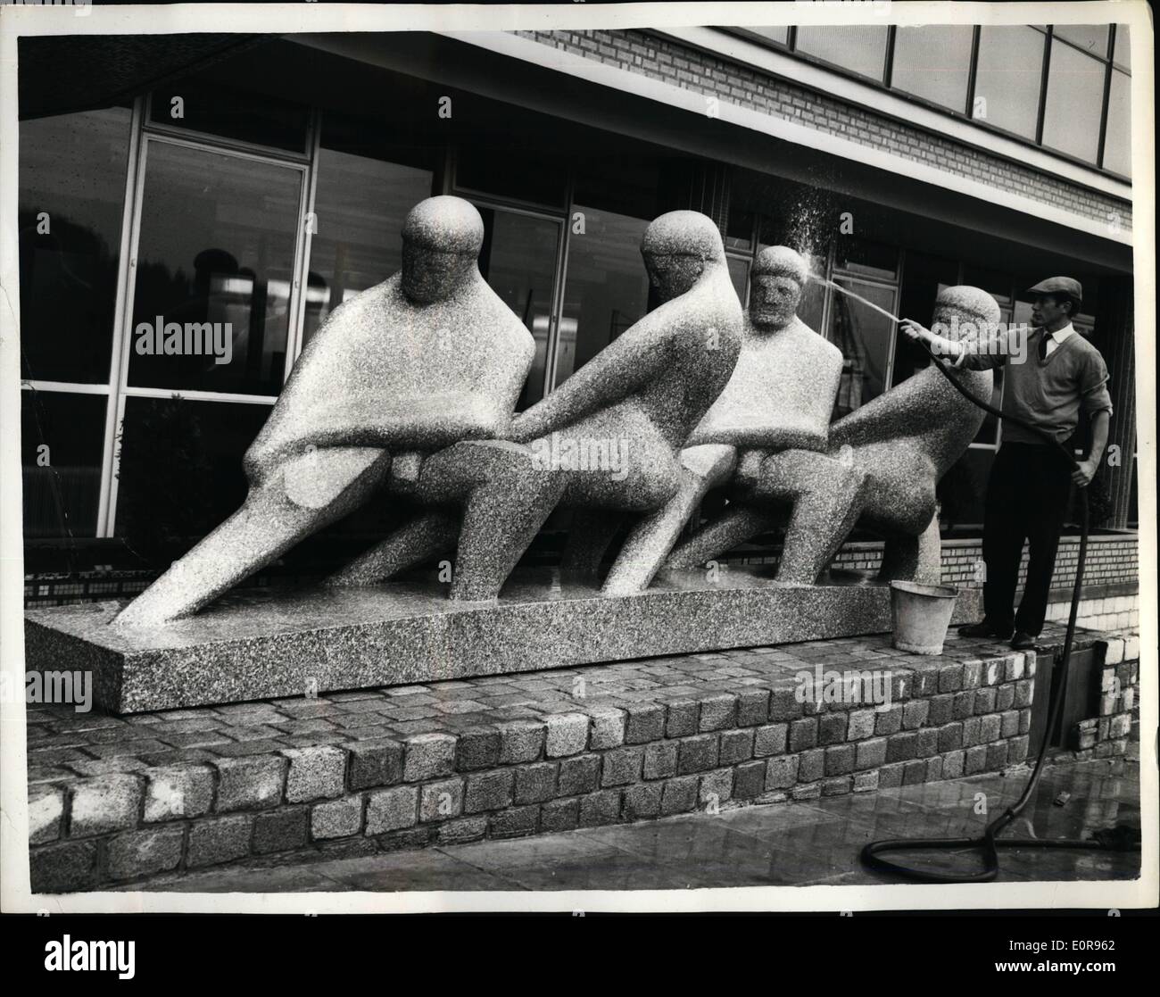 Oct. 10, 1958 - Ten-Ton ''Teamwork'' sculpture; ''Teamwork'' a huge ten-ton granite sculpture by Mr. David Wynne, was this morning put into position outside ''Western House'', Ealing, the new headquarters of the overseas companies within the Taylow Woodrow Group of building and civil engineering concerns, where it is to be unveiled on Monday. The sculpture, which depicts four men pulling one rope, was shaped from a 100 ton rock dynamited from a quarry in Falmouth. Photo Shows The sculpture, Mr. David Wynne, hosing down the sculpture, after it had been placed into position today. Stock Photo