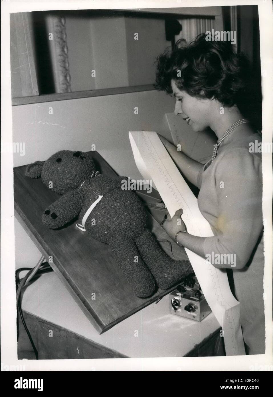 Jan. 01, 1959 - Physical Society Exhibition of Scientific Instruments. ''Teddy Bear'' as a 'Baby': The Physical Society Exhibition of Scientific Instruments and Apparatus is now in progress at the Royal Horticultural Hall, Westminster. Photo shows Mrs. Juan Rose of Cambridge examining a device for the investigation of faulty breathing in small babies, developed by the University Department of Anaesthetics. A tube filled with graphite is strapped across the chest which lengthens or shortens as the baby breather in and out. This Changers the resistance which is recorded on an oscillograph Stock Photo