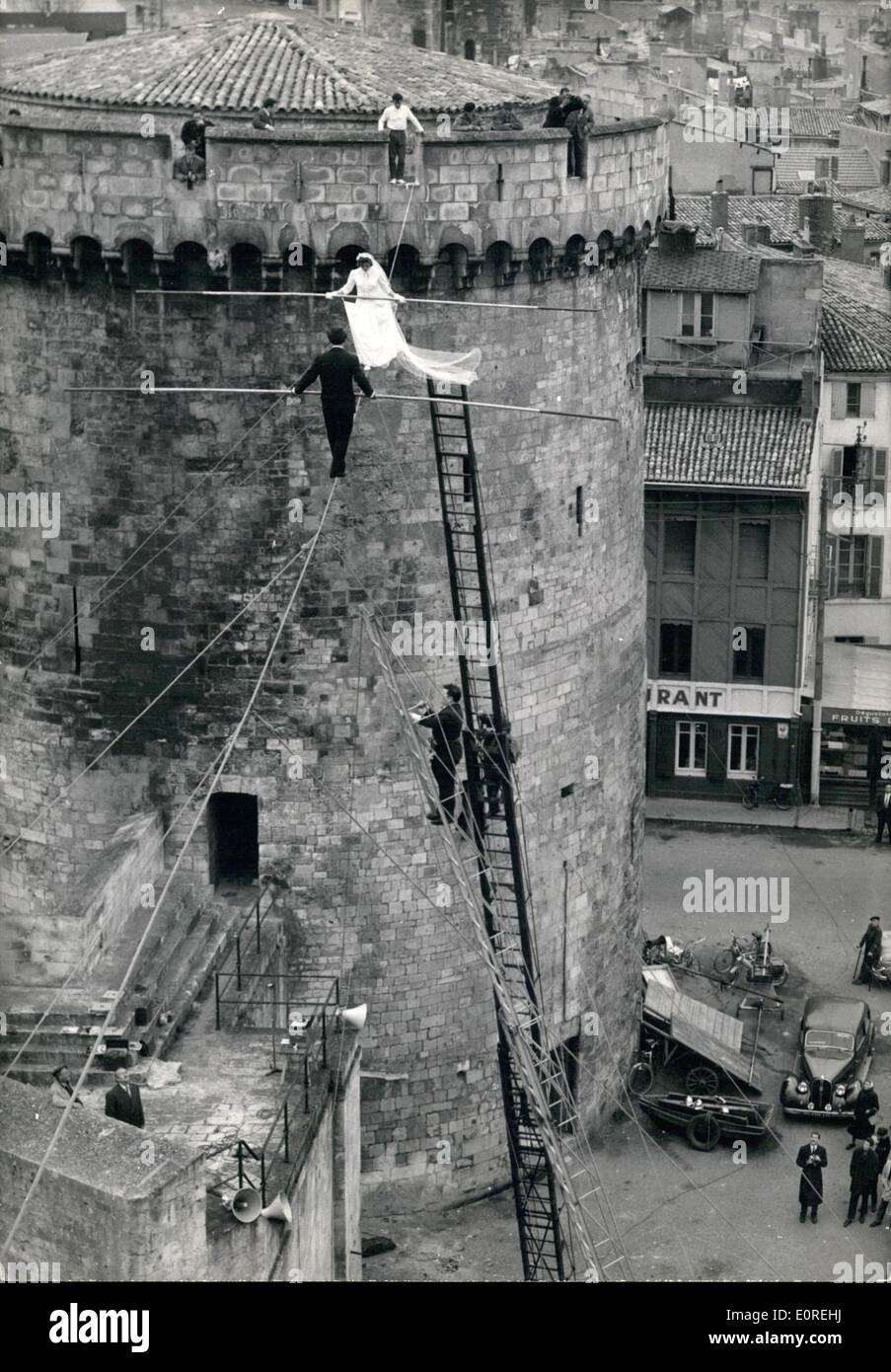 Mar. 03, 1959 - Wedding On A Tight Rope: A couple of tight rope acrobats, Roland Schmidt, 19n and Francine Pary, 19, from La Rochelle, near Bordeaux, were married on a tight rope in the la Rochelle harbour yesterday. The rope was fixed between two ancient towers 60 feet above the ground. A well-known cabaret singer, Claude Bejac, deputising for the mayor of the free community of montmartre, united the couple while standing on a firemen's ladder. photo shows. Bride and bridegroom being married on the tight rope. Below, on a ladder, Claude Bejac. Stock Photo