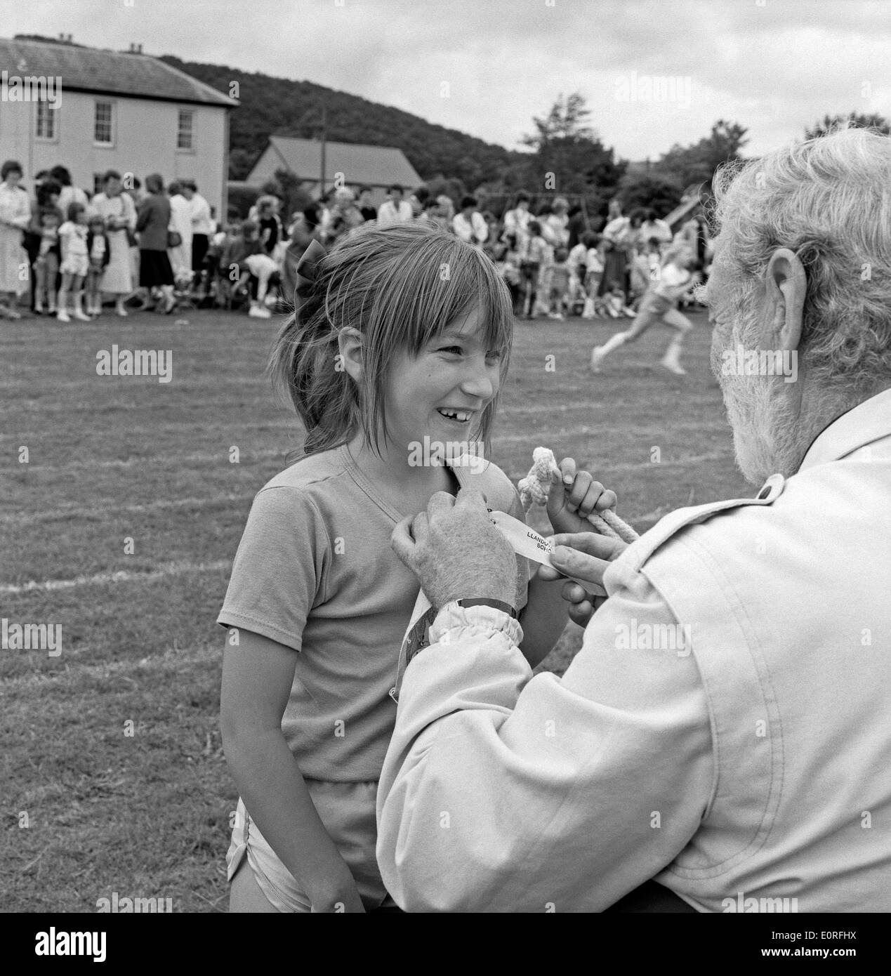 A judge pins a ribbon onto a girl's t shirt at primary school sports day in Llanwrda, Carmarthenshire Wales UK  KATHY DEWITT Stock Photo