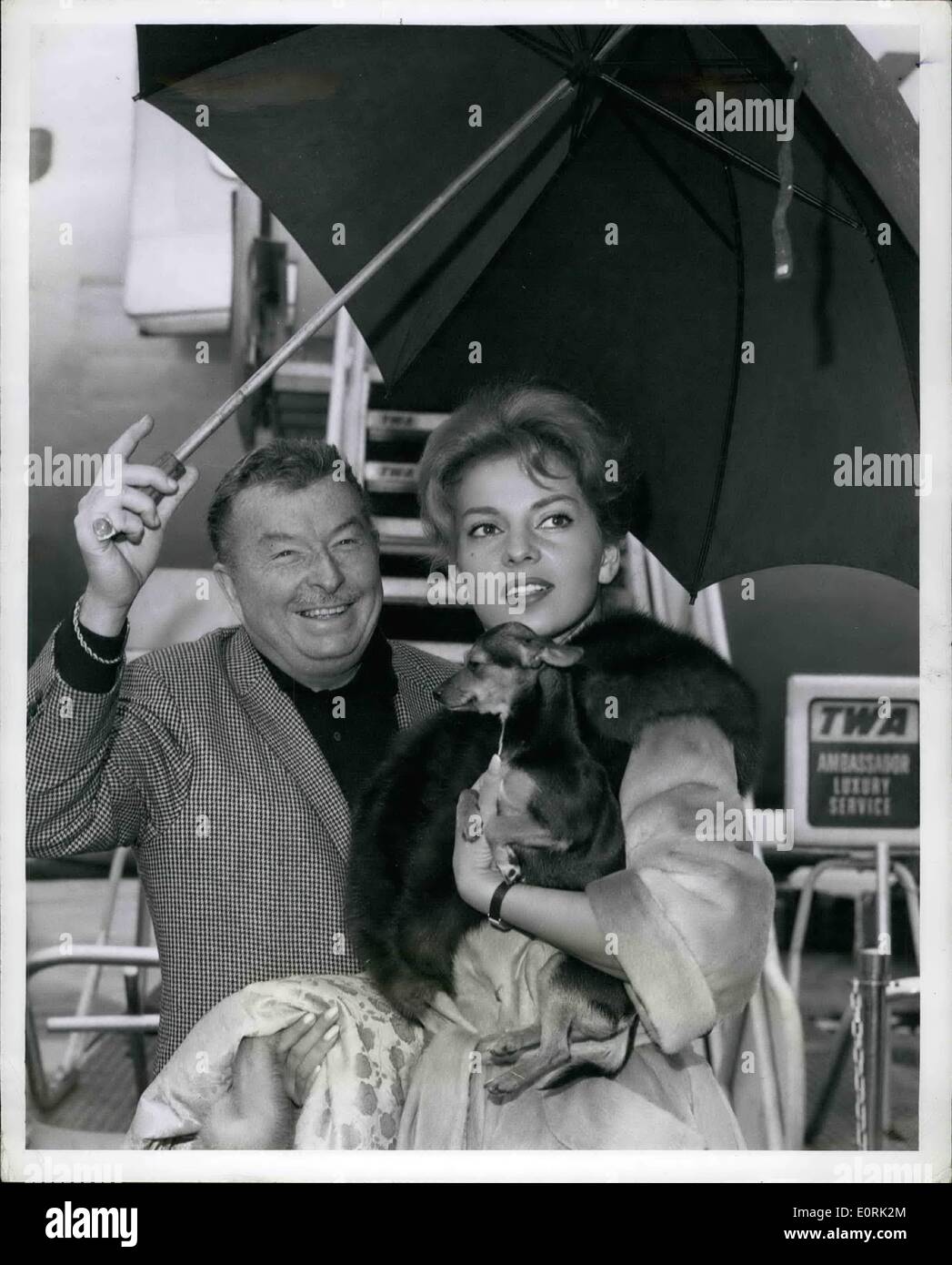 Dec. 12, 1959 - Our Fog covered airport received a bright lift in the from of lovely Abbe Lane pictured here with her husband, Xavier Cugat and their pet ''Susie'' prior to boarding a TWA liner to Los Angeles. They will be back with us in four weeks after they complete a night club engagement in Palm springs, California. Stock Photo